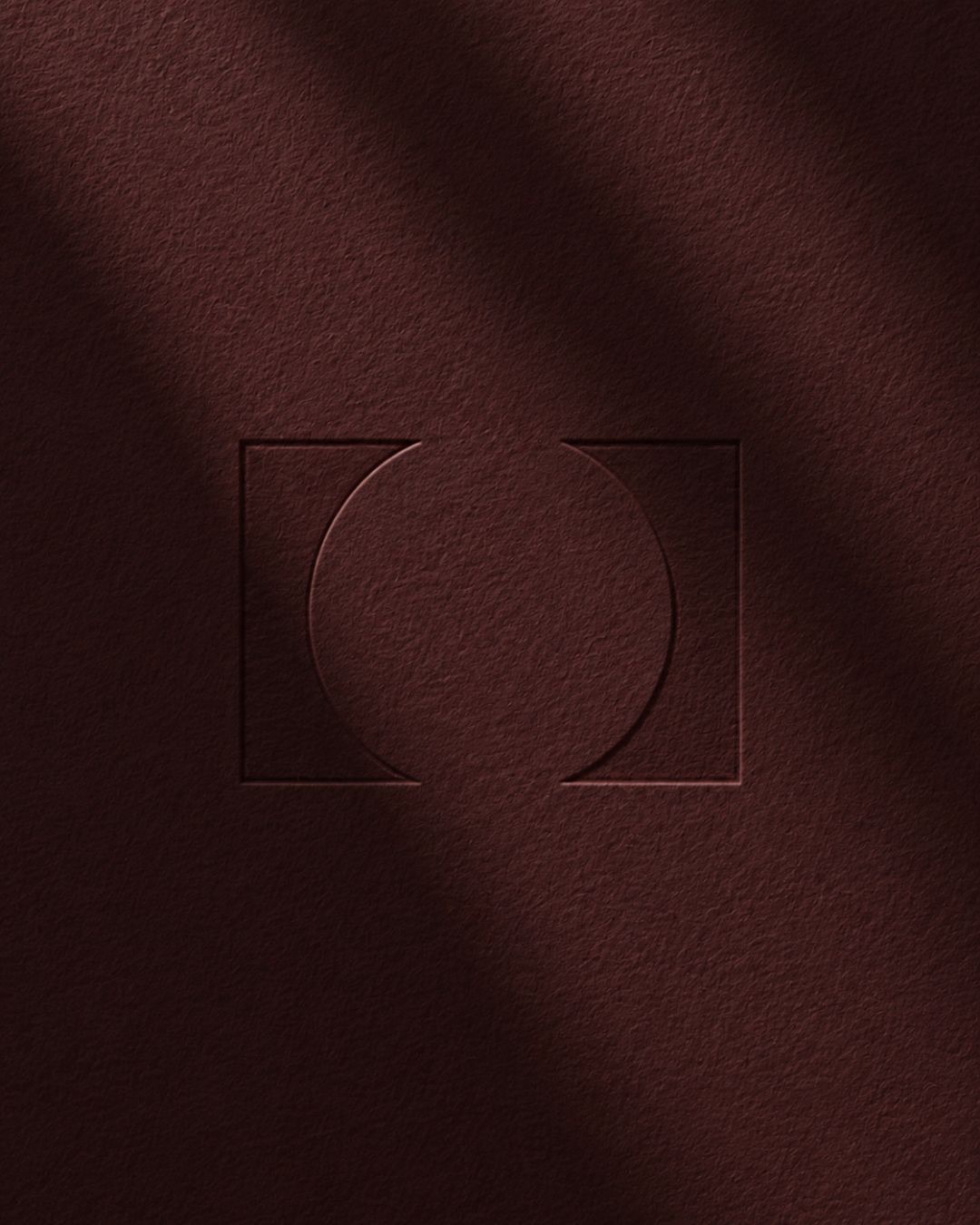 Embossed Portal logomark on deep burgundy textured surface