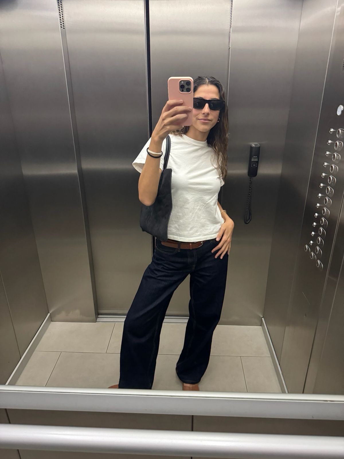 White tee, dark wide-leg jeans and a suede tote in an elevator mirror selfie