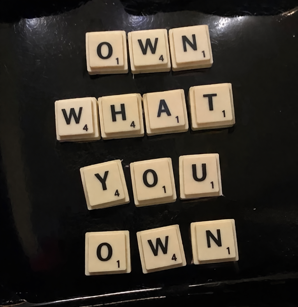 Scrabble tiles spelling 'Own what you own'